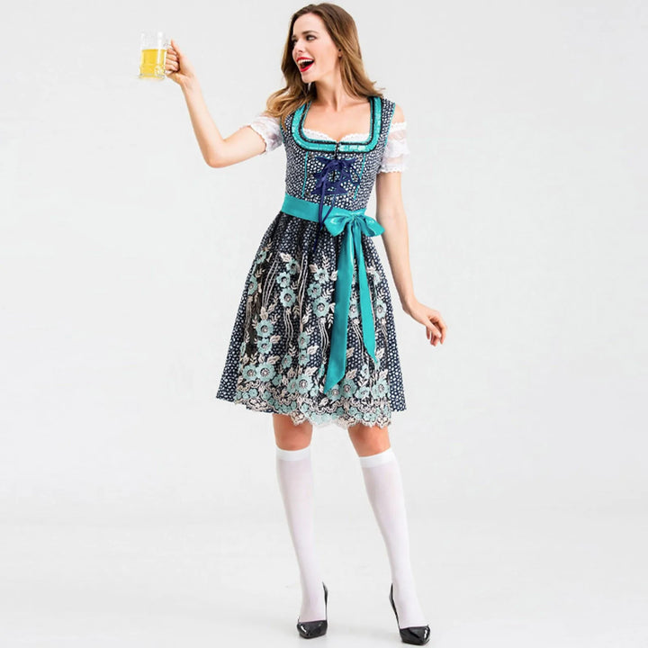 Frau im blauen Dirndl mit Blumenmuster, hält Bierkrug, Oktoberfest, traditionelle Tracht.