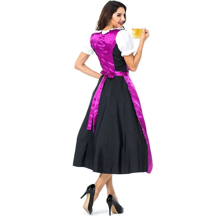 Frau im traditionellen Dirndl mit lila Schürze, hält Bierkrug, Oktoberfest-Kleidung.