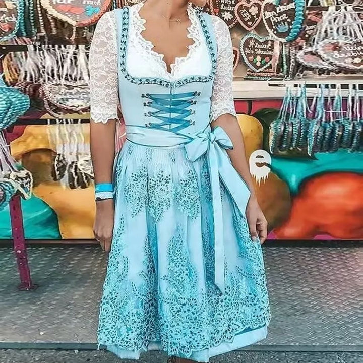 Frau im blauen Dirndl mit Spitzenbluse vor Lebkuchenherzen-Stand auf Oktoberfest.