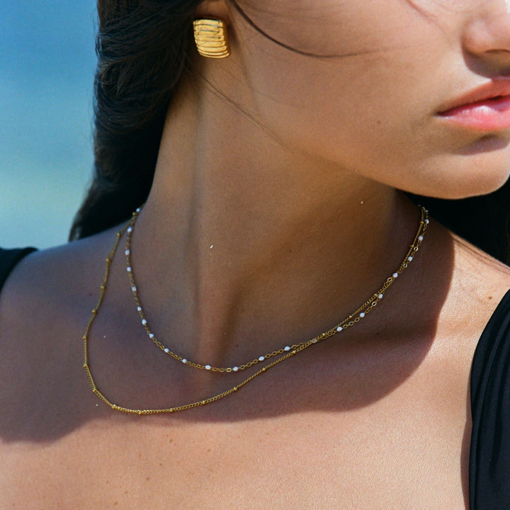 Goldene zweilagige Halskette, Damenmode, eleganter Schmuck, Strandhintergrund.