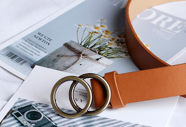 Brauner Designer-Gürtel mit Doppelring-Schnalle aus Metall auf Zeitschriften.