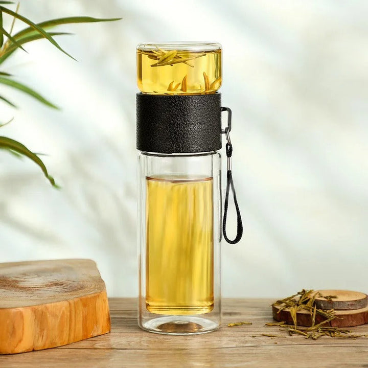 Doppelwandige Glas-Teeflasche mit schwarzem Ledergriff, ideal für unterwegs.