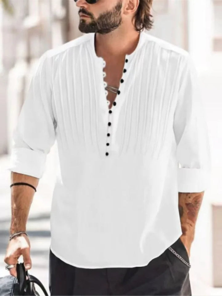 Mann in weißem Leinenhemd mit Stehkragen und schwarzen Knöpfen, lässiger Sommerlook.