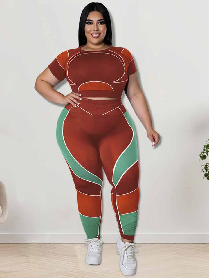 Frau in rot-grünem Sportanzug, Plus-Size, lächelt, steht vor weißer Wand, weiße Turnschuhe.