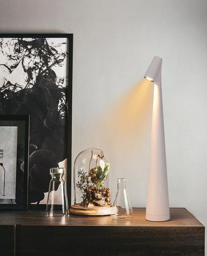 Moderne weiße Tischlampe, konisch, LED, auf Holzschrank neben Pflanzen und Kunstwerk.