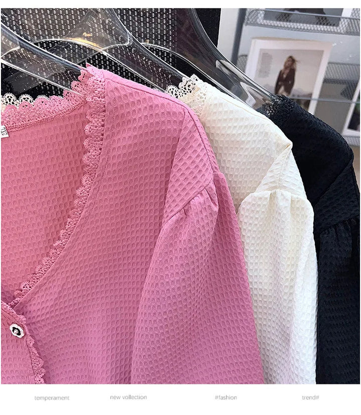 Rosa, weiße und schwarze Blusen aus Waffelstoff mit Spitzenbesatz auf Kleiderbügeln.