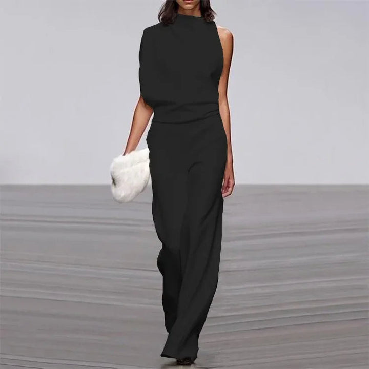 Frau in schwarzem ärmellosen Jumpsuit mit weißer Fell-Clutch auf Laufsteg.