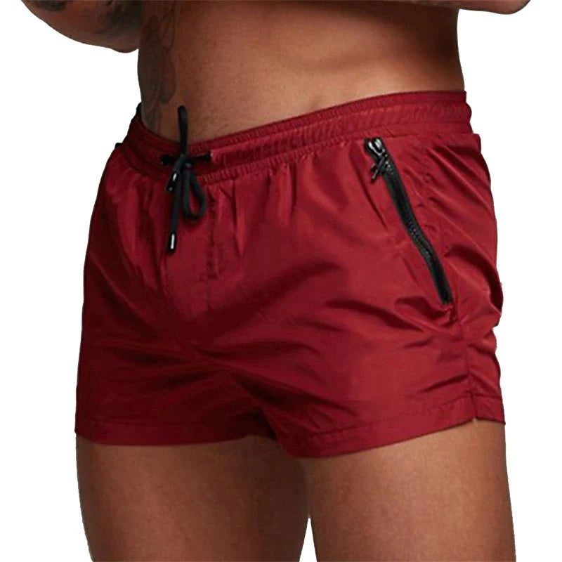 Rote Herren-Badeshorts mit Kordelzug und Reißverschlusstaschen, ideal für Sommer und Strand.