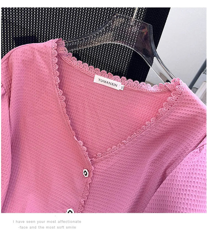 Rosa Damenbluse mit Spitzenkragen, Knopfleiste, Waffelstruktur, auf Kleiderbügel.