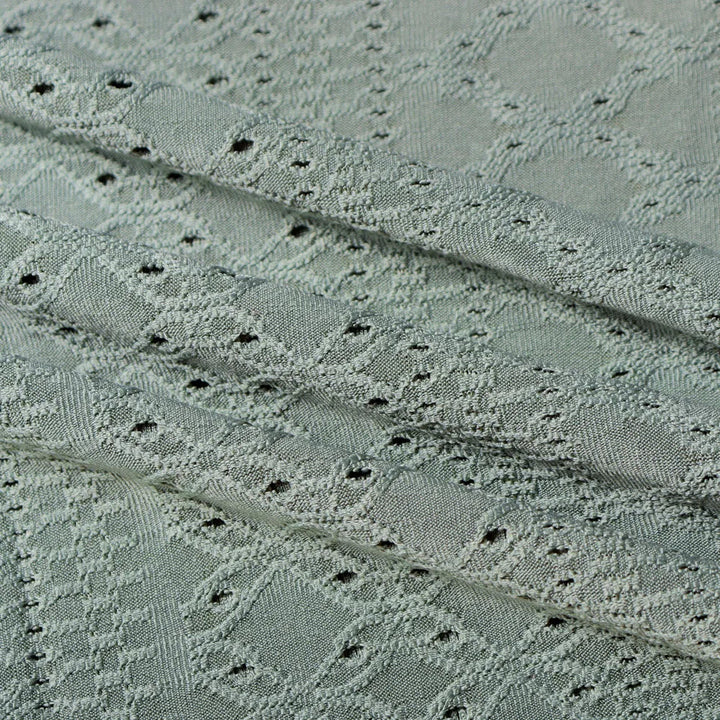 Grauer Jacquardstoff mit geometrischem Muster, ideal für elegante Bekleidung und Heimtextilien.