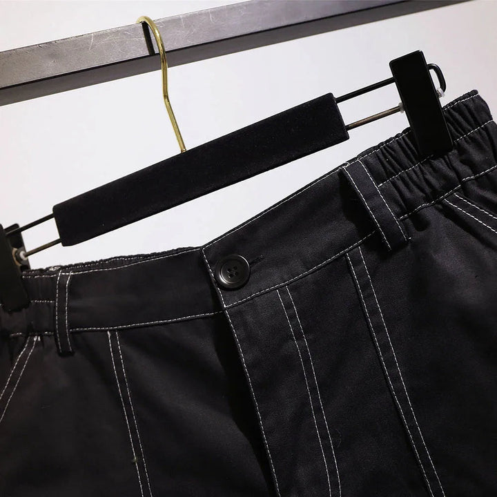 Schwarze Herrenhose mit weißen Nähten, elastischer Bund, auf Kleiderbügel.