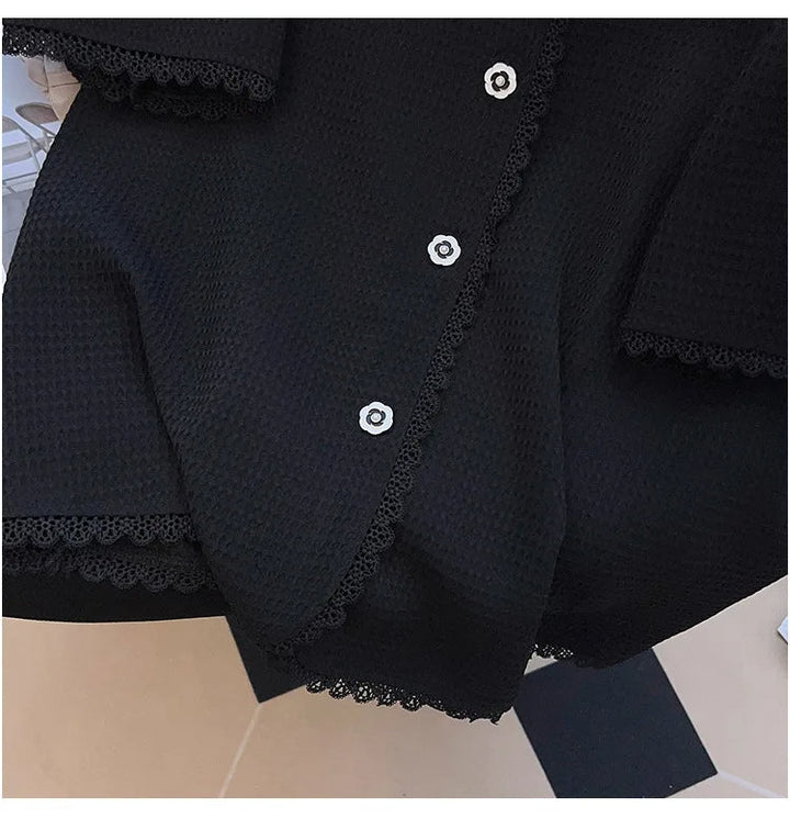 Schwarze Strickjacke mit Spitzenbesatz und Knöpfen, elegante Damenmode, Nahaufnahme.