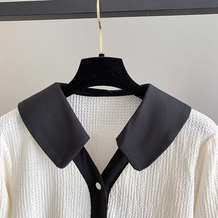 Weiße Strickbluse mit schwarzem Kragen, elegantes Design, Damenmode, hochwertige Materialien.