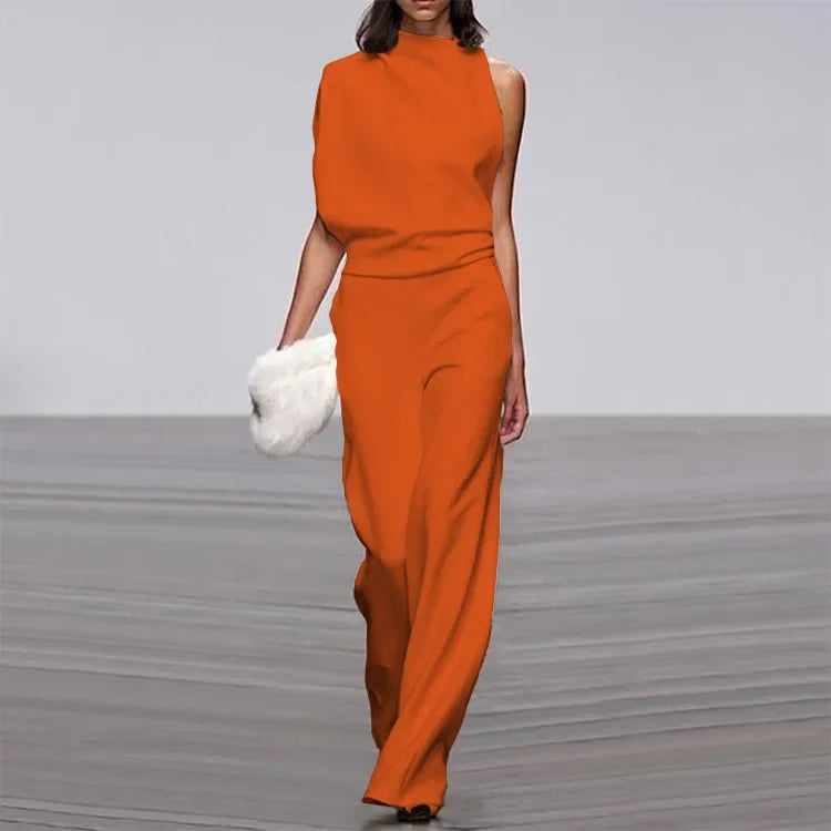 Frau in orangefarbenem, ärmellosem Jumpsuit mit weißer Clutch auf Laufsteg.