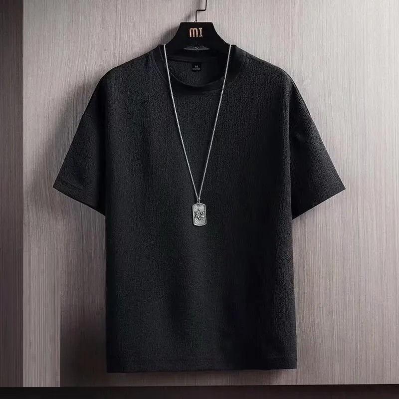 Schwarzes T-Shirt aus Baumwolle mit Rundhalsausschnitt, hängend an Holzkleiderbügel.