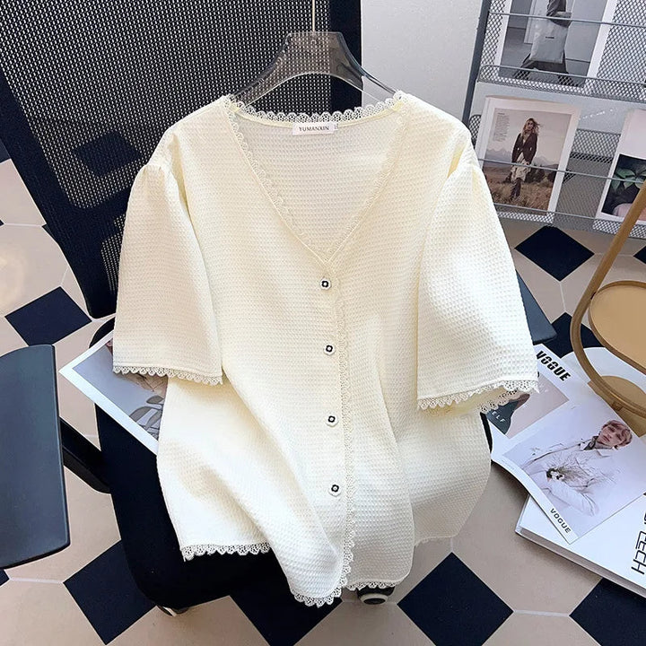 Weiße Strickjacke mit Knöpfen, V-Ausschnitt, Spitzenbesatz, Damenmode, elegant, auf Stuhl.