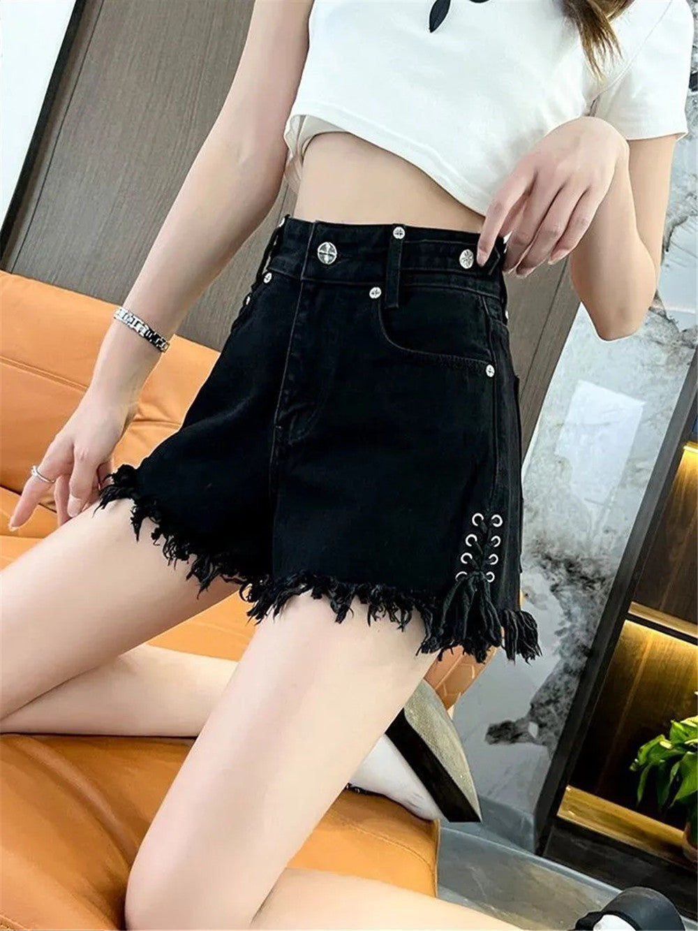 Frau trägt schwarze Jeansshorts mit Fransen, modisch, lässig, Sommerkleidung, Damenmode.