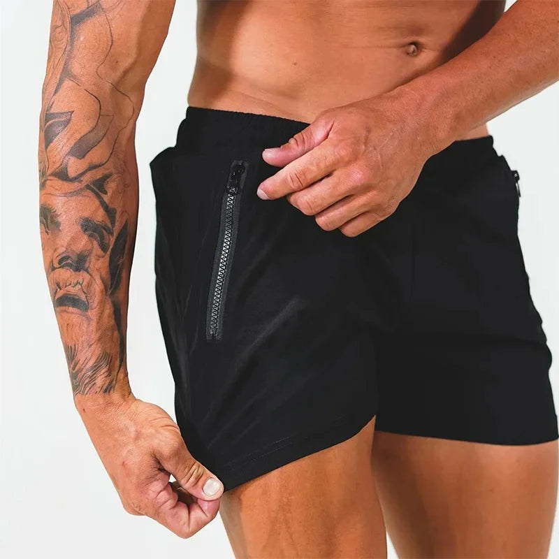 Mann in schwarzen Sportshorts mit Reißverschlusstasche, tätowierter Arm, Fitnessmode.