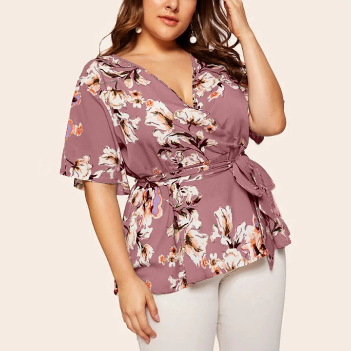 Frau in lila geblümter Bluse mit Gürtel, V-Ausschnitt, kurze Ärmel, Plus-Size-Mode.