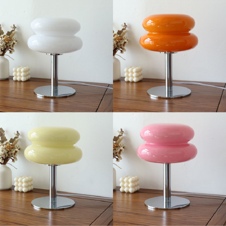 Moderne Tischlampe aus Glas in Weiß, Orange, Gelb und Rosa auf Holztisch, dekorative Beleuchtung.