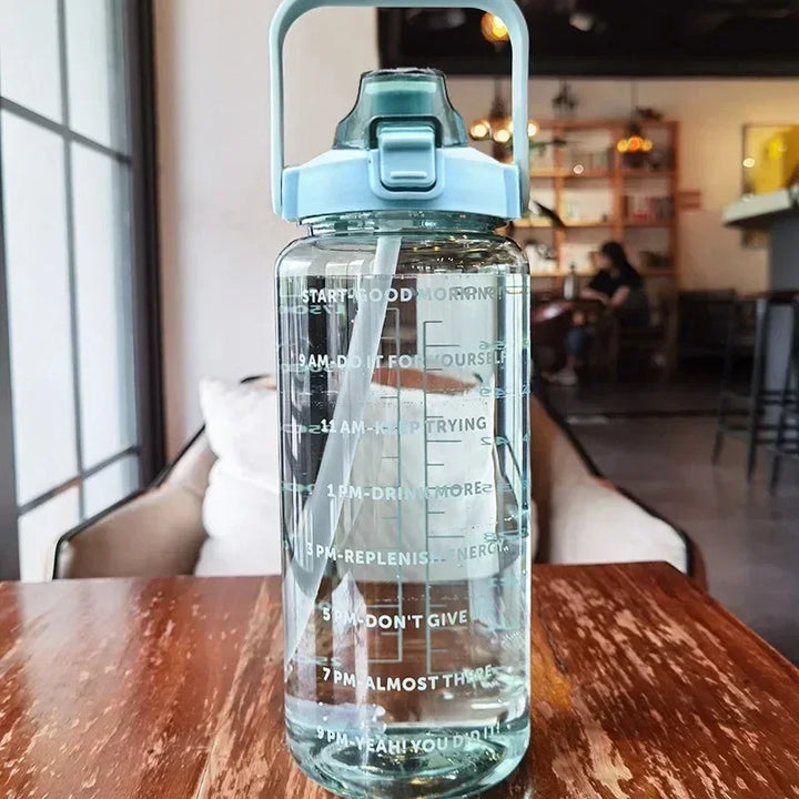 Transparente Wasserflasche mit Zeitmarkierungen, blauer Deckel, motivierende Trinkziele.
