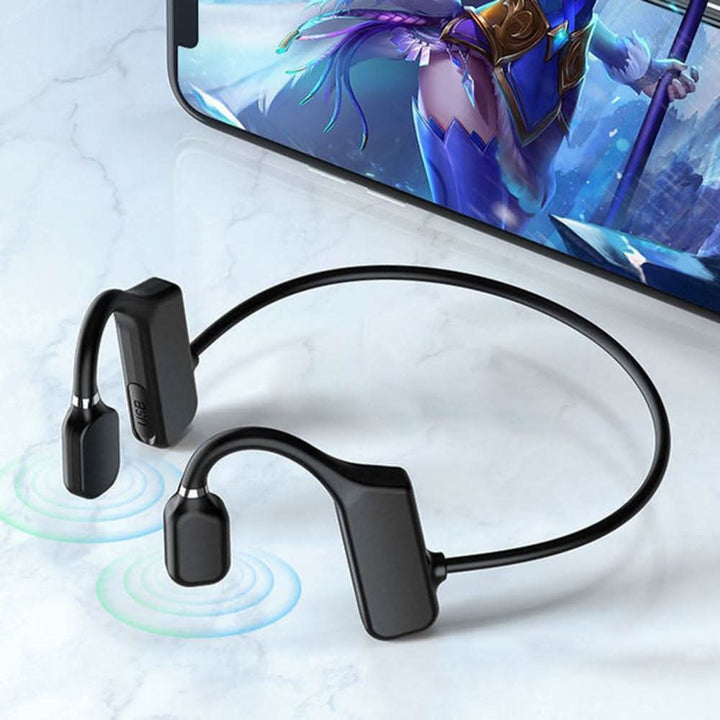 Drahtlose schwarze Knochenschall-Kopfhörer, Bluetooth, neben Smartphone, auf Tisch.
