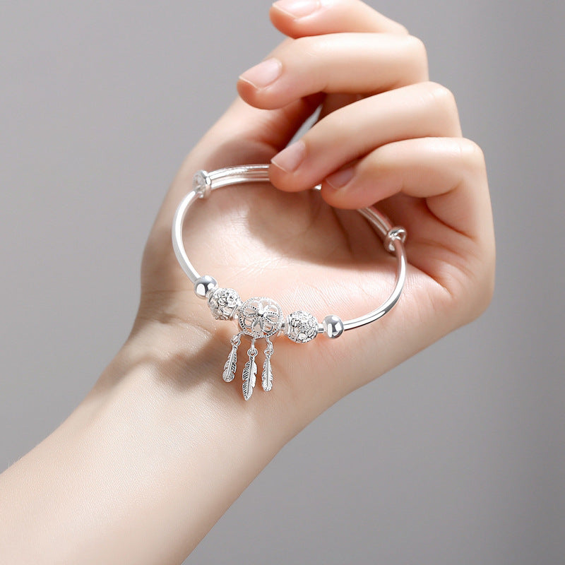 Silbernes Traumfänger-Armband mit Federn, handgehalten, elegantes Schmuckdesign.