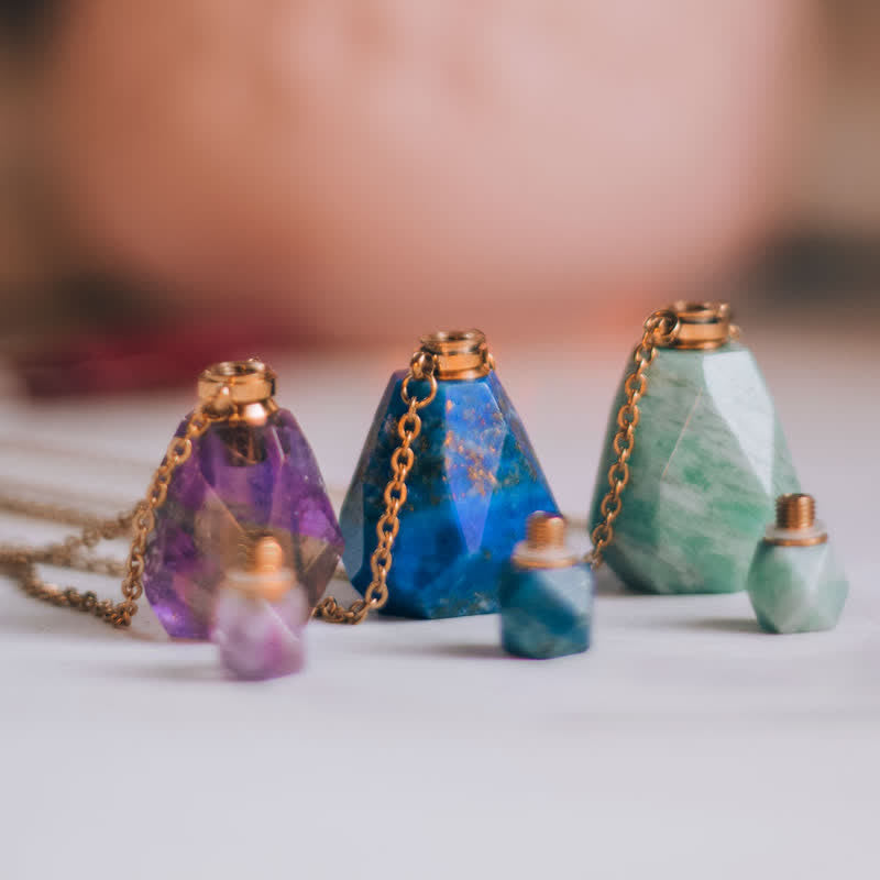 Drei facettierte Edelsteinflaschen mit Ketten, lila, blau und grün, auf weißem Hintergrund.