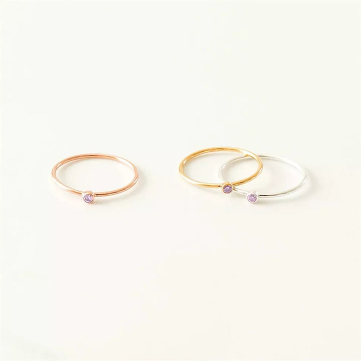 Drei zarte Ringe in Roségold, Gold und Silber mit lila Stein, minimalistischer Schmuck.