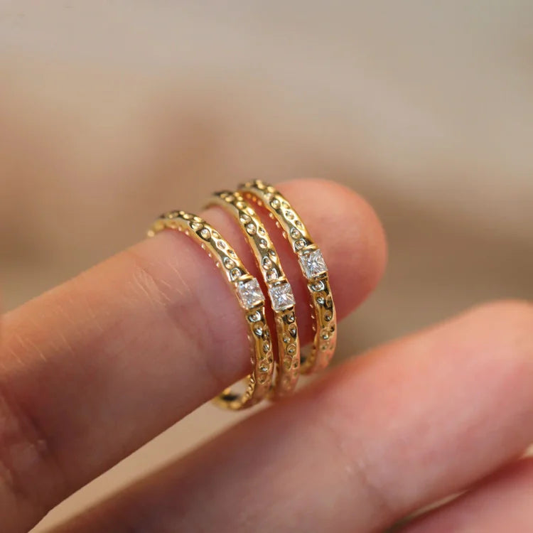 Drei goldene Ringe mit Diamanten, filigran, stapelbar, Schmuck für Damen, elegantes Design.