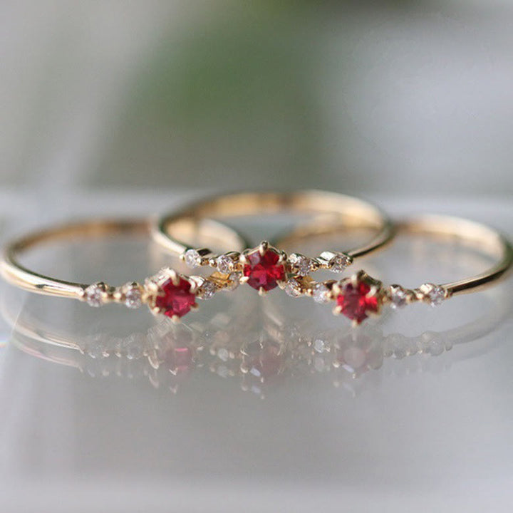 Drei goldene Ringe mit roten Edelsteinen und Diamanten, eleganter Schmuck, Nahaufnahme.