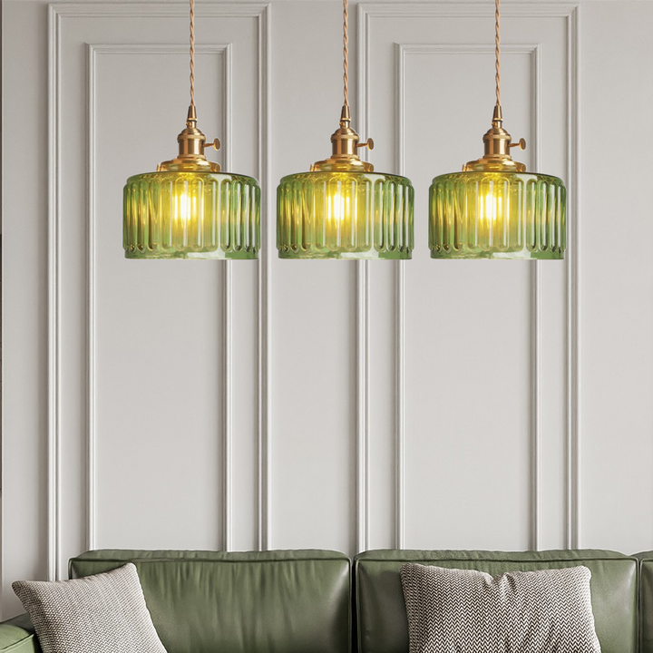 Drei grüne Glas-Pendelleuchten über grünem Sofa, modernes Wohnzimmerdesign, elegante Beleuchtung.