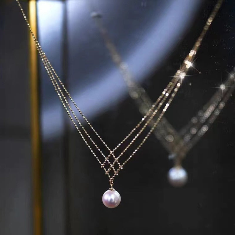 Goldene Halskette mit Perlenanhänger, eleganter Schmuck, reflektiert im Spiegel.