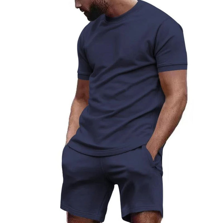 Mann in dunkelblauem T-Shirt und Shorts, Freizeitkleidung, Sommermode, Herrenbekleidung.