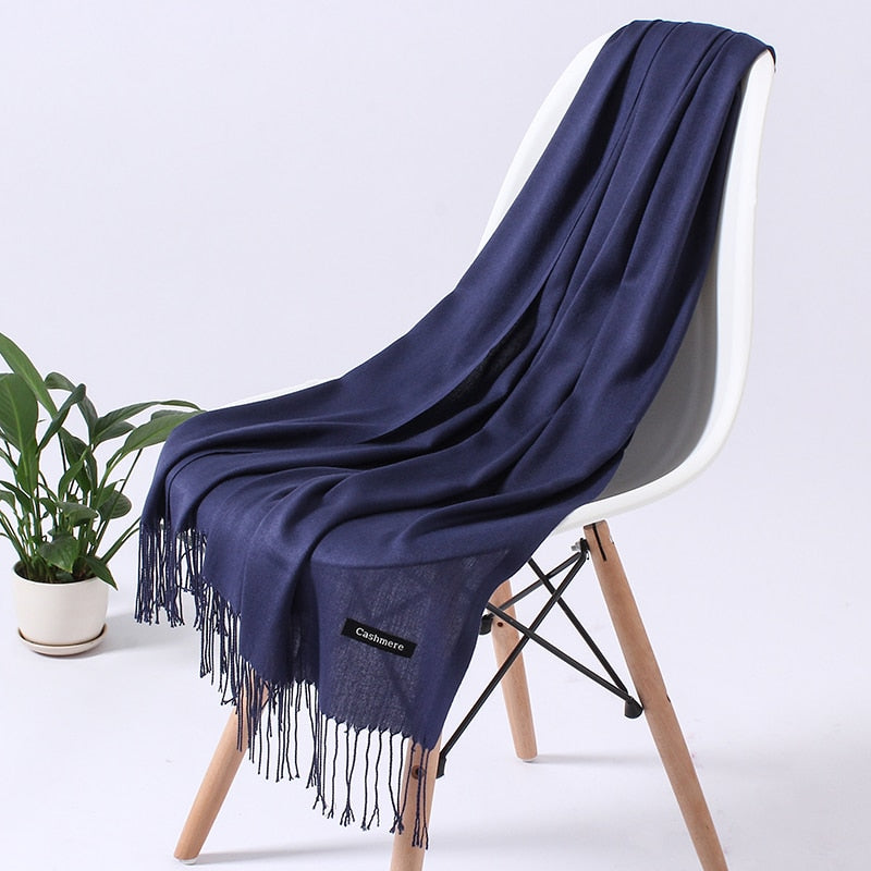 Dunkelblauer Kaschmirschal auf Stuhl, weiches Material, elegantes Design, Fransen, luxuriös.