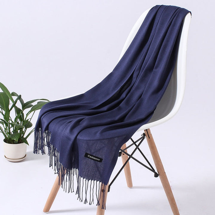 Dunkelblauer Kaschmirschal auf Stuhl, weiches Material, elegantes Design, Fransen, luxuriös.