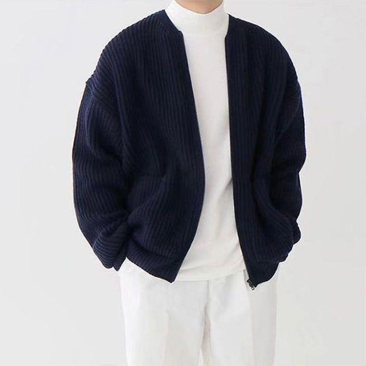 Dunkelblaue Strickjacke für Herren, gerippt, lässig, über weißem Rollkragenpullover.