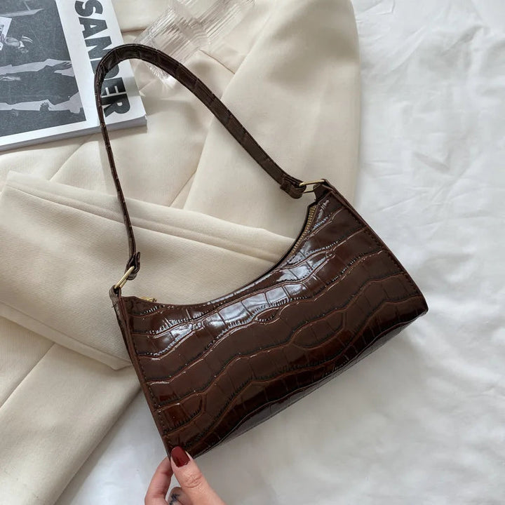 Dunkelbraune Handtasche aus Krokodilleder, elegant, modisch, Damenaccessoire, auf weißem Hintergrund.