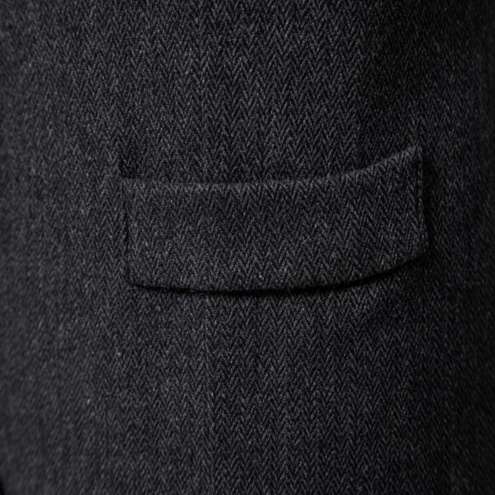 Dunkelgrauer Wollstoff mit Fischgrätmuster, Detailansicht einer Anzugtasche.