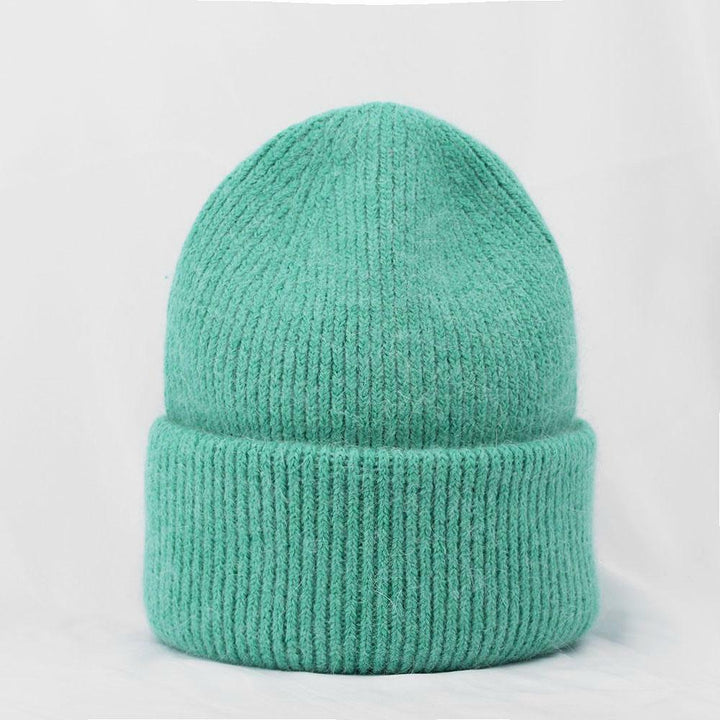 Dunkelgrüne Strickmütze aus Wolle, warm und modisch, ideal für Winterkleidung.