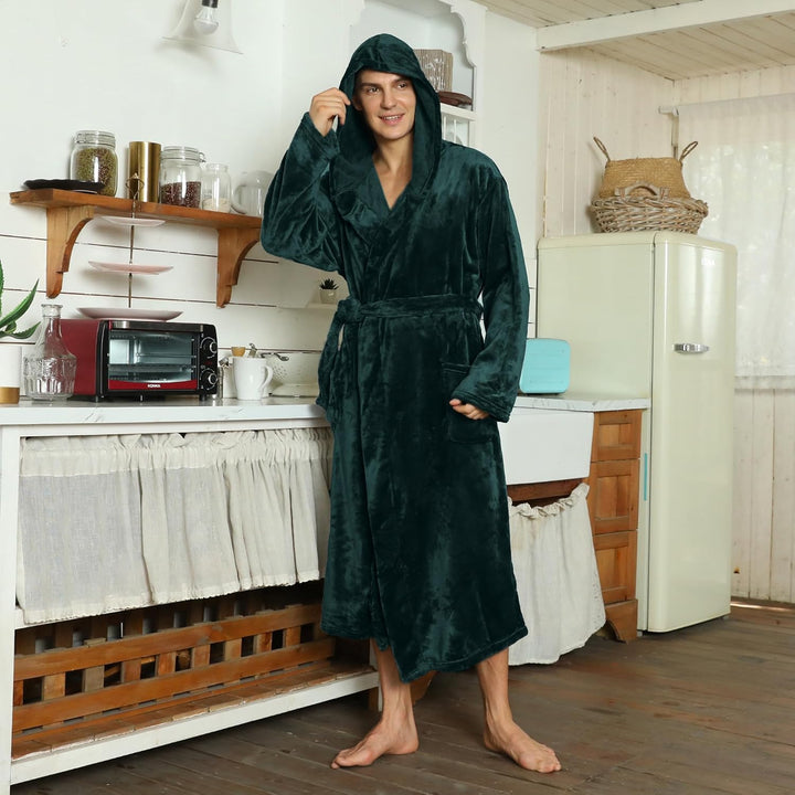 Mann in dunkelgrünem Fleece-Bademantel mit Kapuze in rustikaler Küche.
