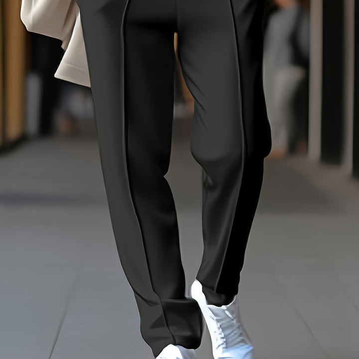 Schwarze Damenhose, elegant, aus Stoff, kombiniert mit weißen Sneakern, modisch, urbaner Stil.