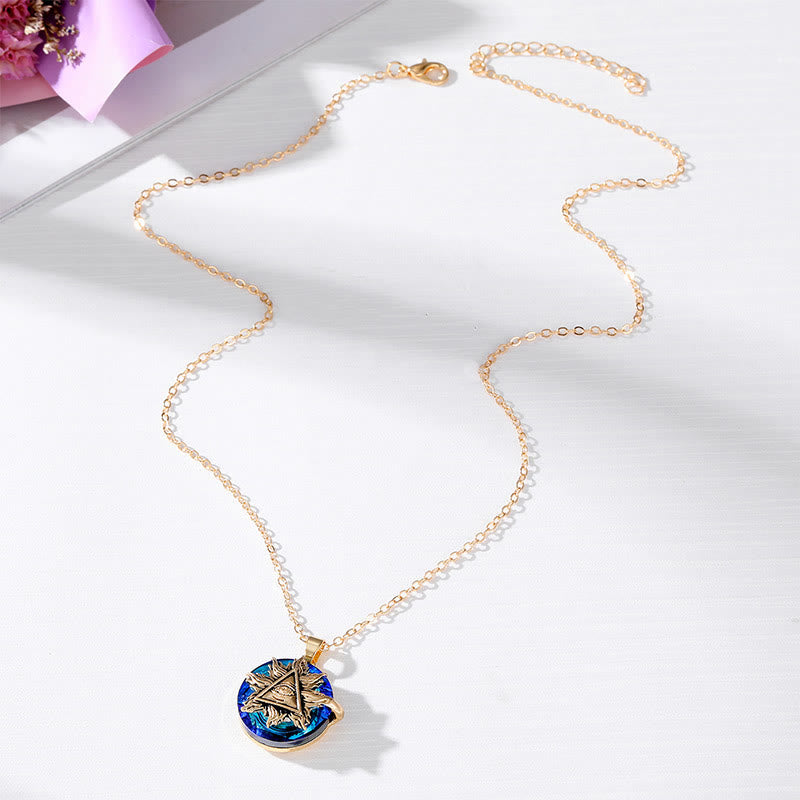 Goldene Halskette mit blauem, rundem Anhänger und Sternmotiv auf weißem Hintergrund.