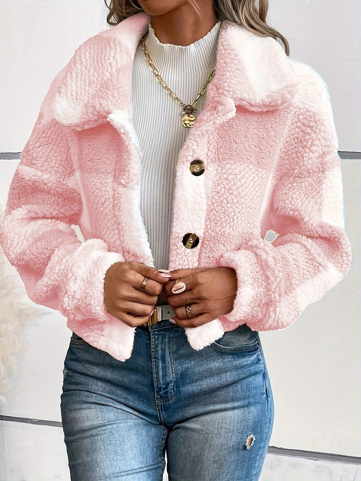 Frau trägt rosa Teddyjacke, weiße Bluse, blaue Jeans, modisch, Wintermode, Damenbekleidung.