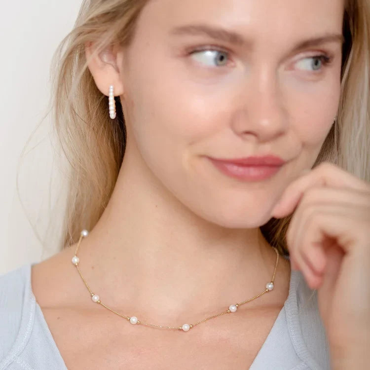 Frau mit Perlenkette und Perlenohrringen, eleganter Schmuck, modisches Accessoire, Nahaufnahme.
