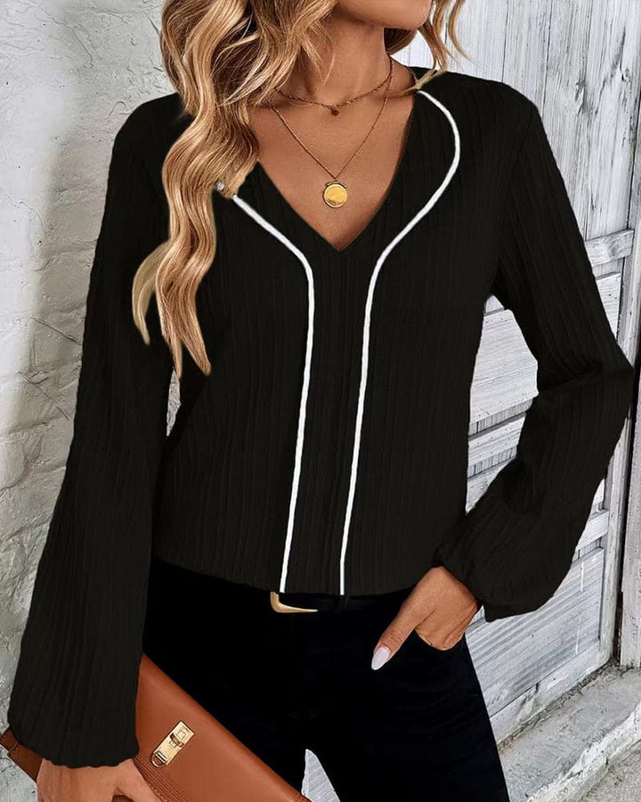 Frau in schwarzer Bluse mit V-Ausschnitt, goldener Halskette, blonde Haare, modisch, elegant.