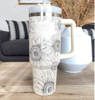 Weißer Thermobecher mit Sonnenblumenmuster, Edelstahl, großer Henkel, auf Holztisch.