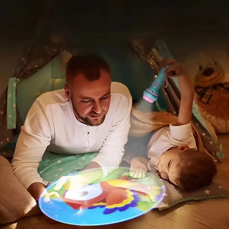 Mann und Kind im Zelt mit Taschenlampe, projizieren bunte Bilder, gemütliche Atmosphäre.