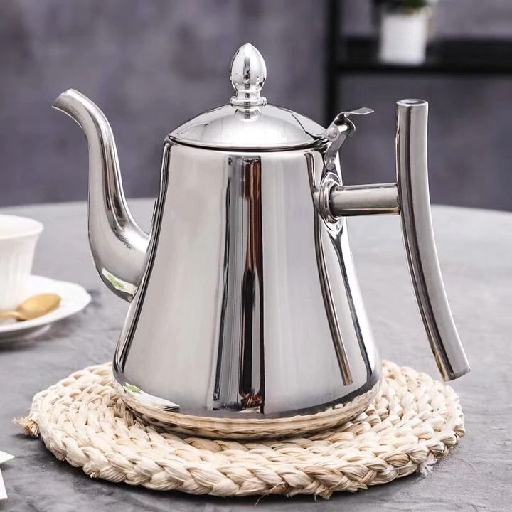 Silberne Edelstahl-Teekanne mit langem Ausguss auf geflochtenem Untersetzer, modernes Design.