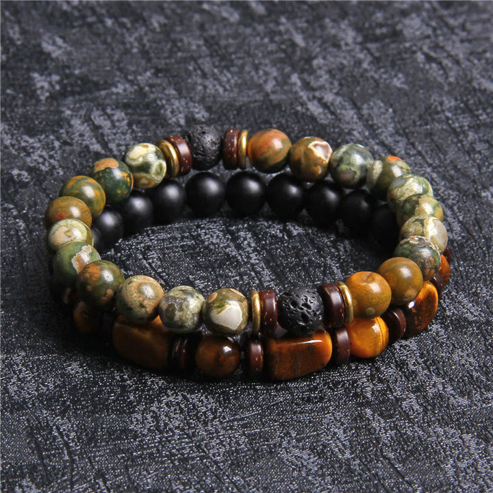 Zwei Armbänder aus Naturstein und Holzperlen, grün und braun, auf schwarzem Hintergrund.